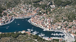 An aerial view of a coastal town with a marina, houses with red roofs, and a hilly landscape. - Holiday Home in Milna with Terrace, Air condition, WIFI, Washing machine (5123-1) (Milna)
