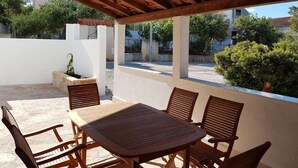 An outdoor patio with a wooden table and chairs, a stone wall, and a view of the surrounding area. - Holiday Home in Milna with Terrace, Air condition, WIFI, Washing machine (5123-1) (Milna)