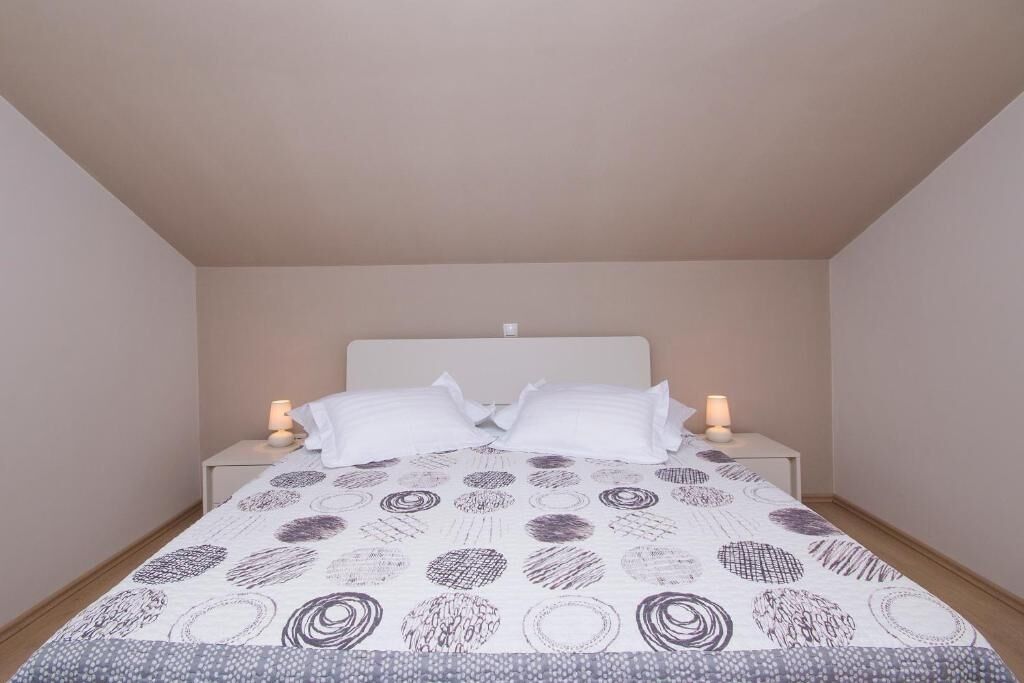 Une chambre à coucher avec un lit, deux tables de chevet et deux lampes fixées au mur.