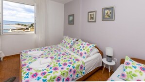 Un dormitorio con cama, una mesita de noche con lámpara y ventana con vista al mar.