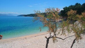 A beach with clear blue water, pebbly shore, and sparse vegetation. - Apartment in Slatine with Seaview, Terrace, Air condition, WIFI (5130-2) (Slatine)
