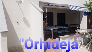 A building with a covered outdoor seating area, a sign reading "Orhideja," and a small table with chairs. - Apartment in Slatine with Seaview, Terrace, Air condition, WIFI (5130-2) (Slatine)