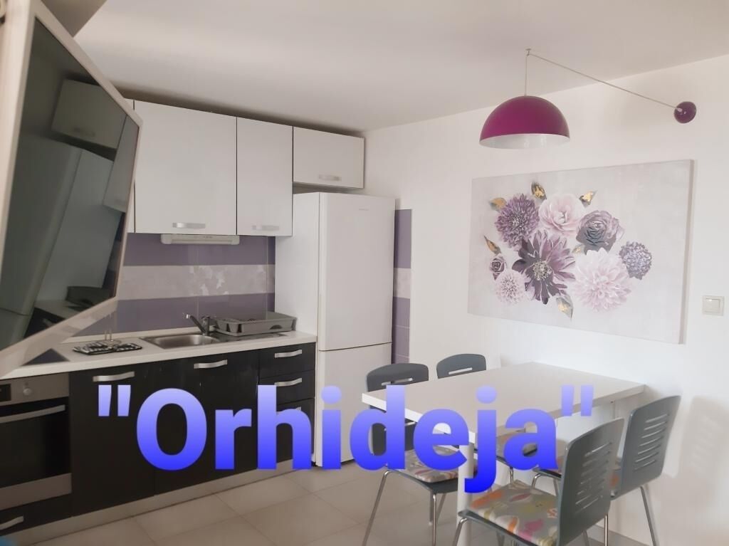 A modern kitchen with white cabinets, a black countertop, and a dining area with a table and chairs.