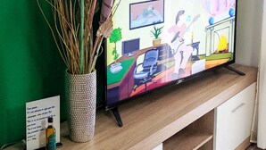 Ein modernes Wohnzimmer mit grüner Wand, einer Holzeinrichtungsanlage, einem Fernseher und einer dekorativen Uhr.