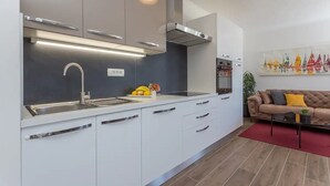 A modern kitchen with white cabinets, a stainless steel sink, and a red rug in the living area. - Apartment in Bol with Seaview, Balcony, Air condition, WIFI (5127-1) (Bol)