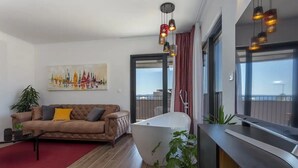 A modern living room with a large window, a sofa, a red rug, a bathtub, and a potted plant. - Apartment in Bol with Seaview, Balcony, Air condition, WIFI (5127-1) (Bol)