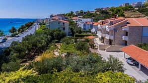 A coastal residential area with houses, a road, and a view of the sea. - Apartment in Dugi Rat with Seaview, Balcony, Air condition, WIFI (5132-4) (Dugi Rat)