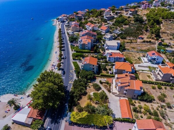 An aerial view of a coastal residential area with houses, a beach, and a road. - Apartment in Dugi Rat with Seaview, Balcony, Air condition, WIFI (5132-4) (Dugi Rat)