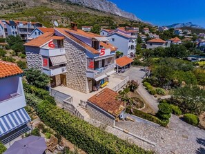 A residential building with numbered balconies, stone facade, and a view of a hillside. - Studio apartment in Dugi Rat with Seaview, Balcony, Air condition, WIFI (5132-5) (Dugi Rat)