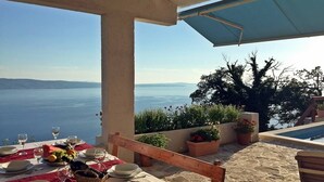 Ein Tisch für ein Essen mit Blick auf das Meer, Sitzgelegenheiten im Freien und Topfpflanzen.