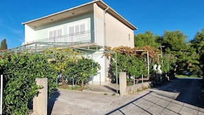 A two-story building with a balcony, surrounded by greenery and a clear blue sky. - Apartment in Okrug Donji with Seaview, Terrace, Air condition, WIFI (5136-1) (Okrug Donji)