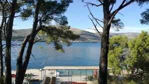 A lakeside view with a covered deck and steps leading to a beach. - Apartment in Okrug Donji with Seaview, Terrace, Air condition, WIFI (5136-1) (Okrug Donji)