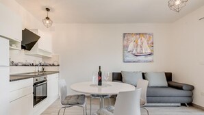 A modern kitchen with white cabinets and a dining area with a round table and chairs.