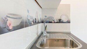 A modern kitchen with a stainless steel sink, white cabinetry, and a backsplash with a ceramic tile design.