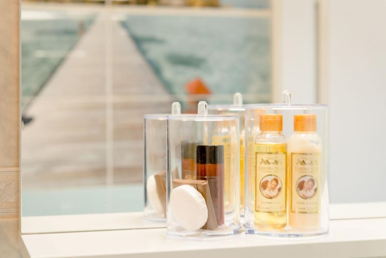 A bathroom with toiletries in clear containers, a window with a view of a dock and water.