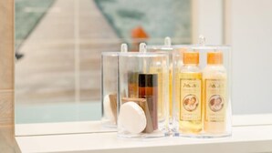 A bathroom with toiletries in clear containers, a window with a view of a dock and water.