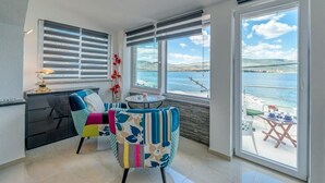 A room with a view of the sea, a dining area with a table and chairs, and a sofa with colorful cushions.