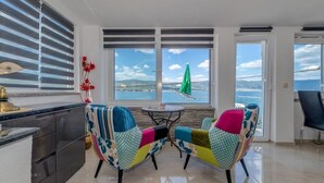 A modern kitchen with a dining area featuring colorful chairs and a view of the sea.