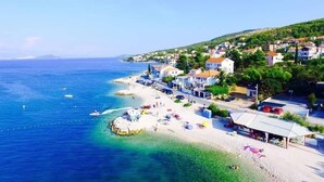 A coastal town with a beach, houses, and a clear blue sea.
