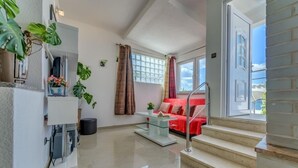 A modern living room with a red sofa, a glass coffee table, and a staircase leading to an upper floor.