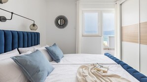 A bedroom with a large bed, a view of the sea, and a balcony.