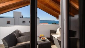 Een balkon met rieten meubilair, een tafel met ontbijtartikelen en uitzicht op zee.