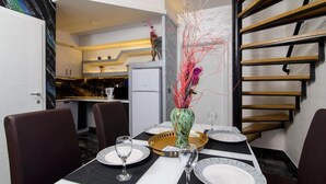 Een eetgedeelte met een tafel gedekt voor twee personen, een vaas met bloemen en een trap met houten treden.