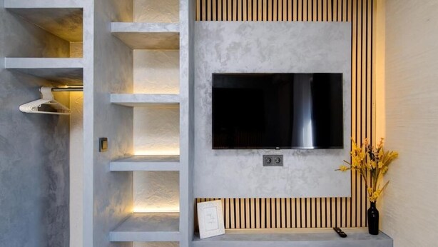 Un intérieur moderne avec un téléviseur encastré, des lambris en bois et un vase rempli de fleurs.