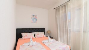 Un lit bien fait, avec une couvre-lit à motifs floraux et des coussins assortis, une tête de lit noire et une petite table de chevet avec une lampe.