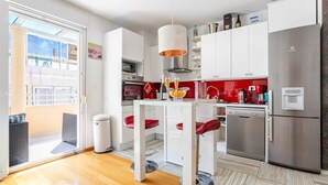 A modern kitchen with white cabinets, a stainless steel refrigerator, and a dining area with a white table and red chairs. - Apartment in Split with Balcony, Air condition, WIFI (5141-1) (Split)