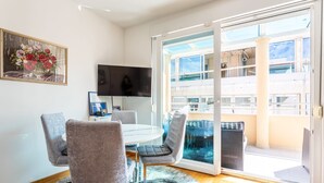 A modern room with a round table, four chairs, a flat-screen TV, and a large sliding glass door leading to an outdoor balcony. - Apartment in Split with Balcony, Air condition, WIFI (5141-1) (Split)