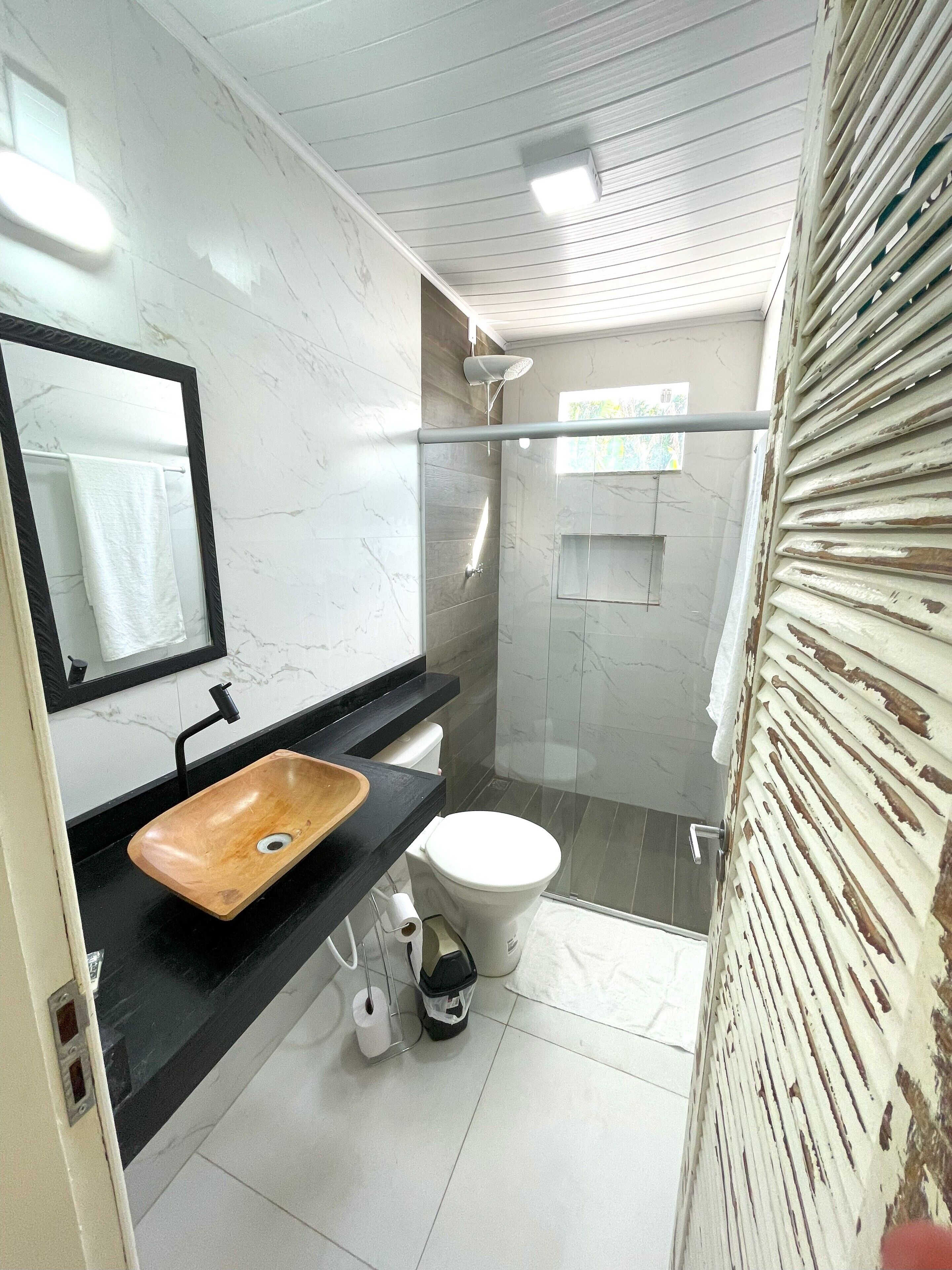 A modern bathroom with a wooden sink, a toilet, and a glass-enclosed shower.