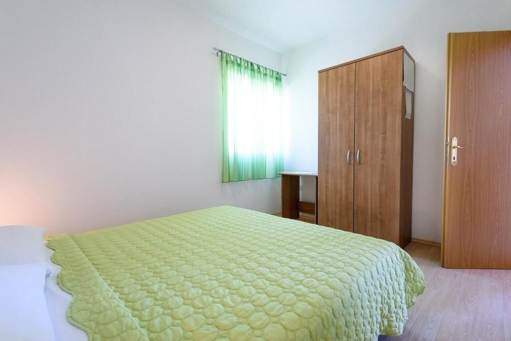 A room with a bed, a wardrobe, and a window with curtains.