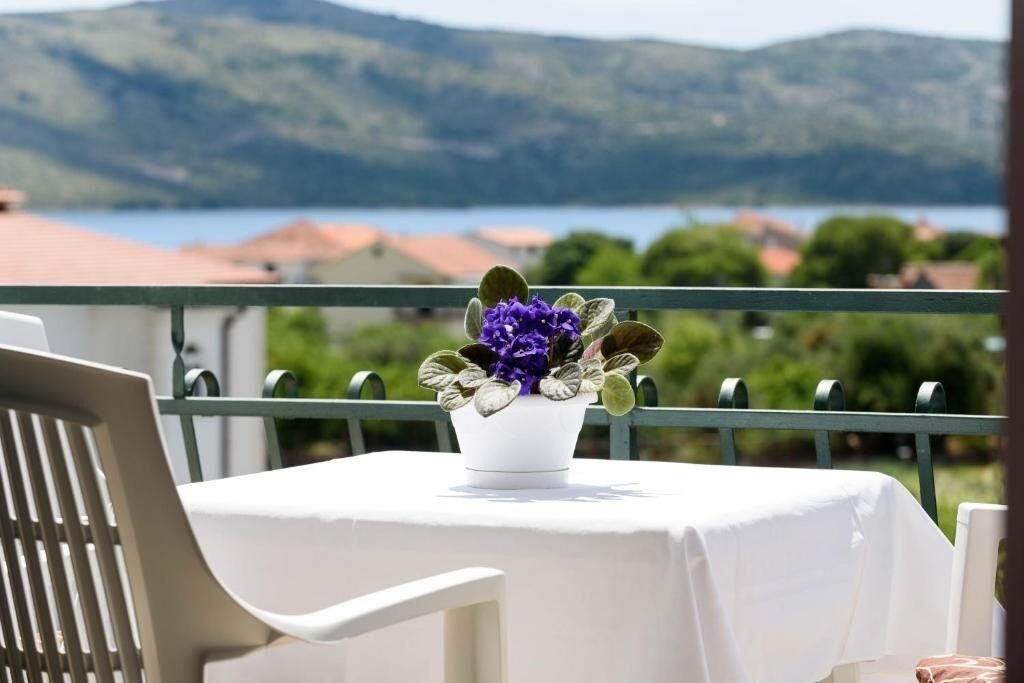 Ein Balkon mit Tisch für zwei Personen, mit Blick auf eine malerische Berg- und Wasserlandschaft.