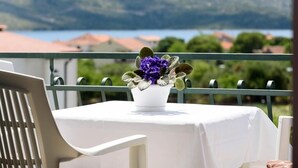A balcony with a table set for two, overlooking a scenic view of mountains and a body of water. - Apartment in Seget Vranjica with Seaview, Balcony, Air condition, WIFI (5142-3) (Seget Vranjica)