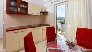 A modern kitchen with beige cabinets and a red dining table with chairs. - Apartment in Seget Vranjica with Seaview, Balcony, Air condition, WIFI (5142-3) (Seget Vranjica)