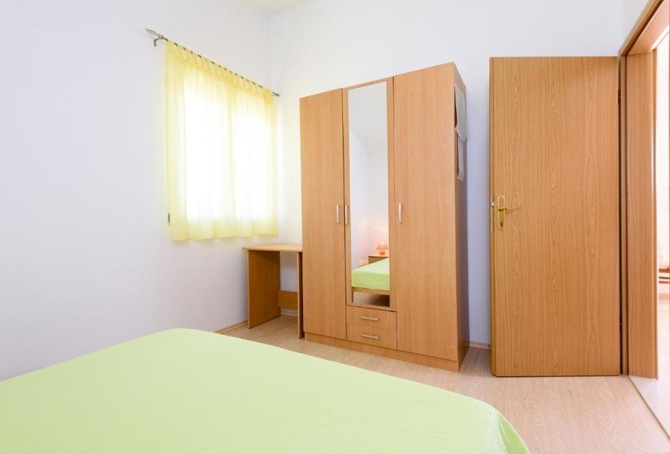 A room with a bed, a wardrobe, a desk, and a window with curtains.