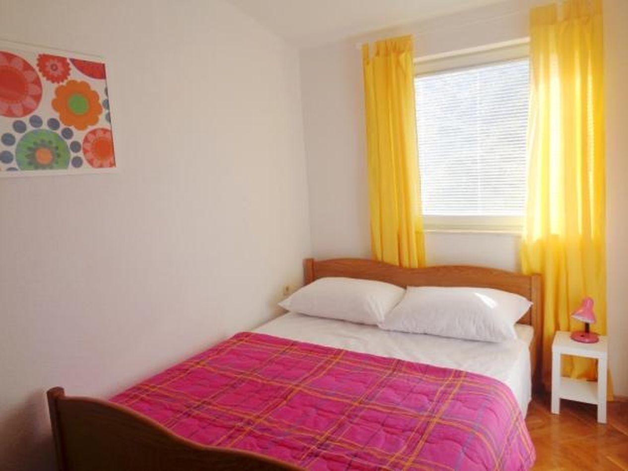 Une chambre à coucher avec un lit, une table de chevet, une lampe et une fenêtre avec des rideaux.
