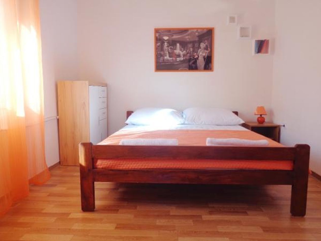 Una camera da letto con un letto di legno, un comodino con una lampada, un armadio e un quadro appeso al muro.