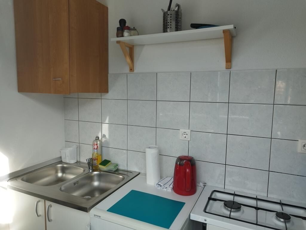 Una cucina con due lavelli in acciaio inossidabile, un piano cottura a gas e uno scaffale sopra il bancone.