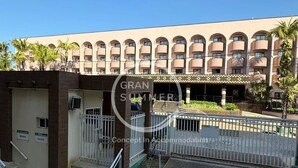 A hotel entrance with a gated driveway, a covered walkway, and a building with multiple balconies. - Gran Summer Concept In Accommodation (Fortaleza)