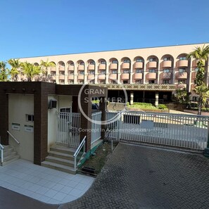 A hotel entrance with a gated driveway, a covered walkway, and a building with multiple balconies. - Gran Summer Concept In Accommodation (Fortaleza)