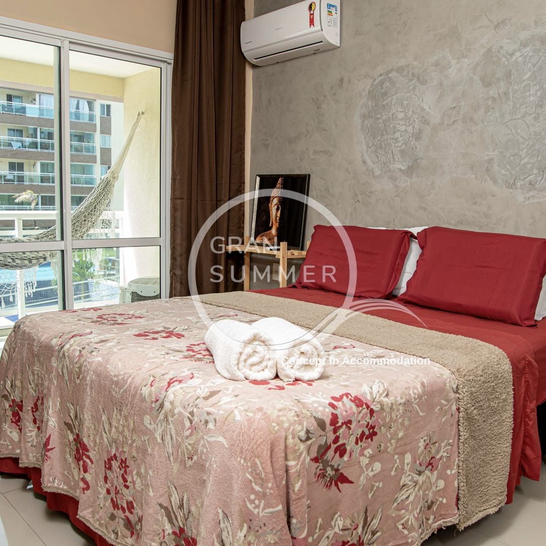 Quarto de hotel com cama, janela e ar condicionado.