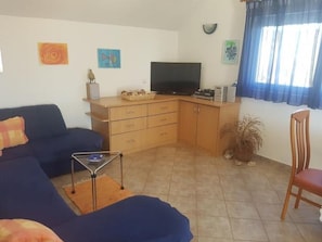 Cozy living space with a sofa, flat-screen TV, and potted plant.