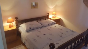 Ein Schlafzimmer mit einem Einzelbett, zwei Nachttischen mit Lampen, einem Holzkopfende und einer kleinen Wanddekoration.