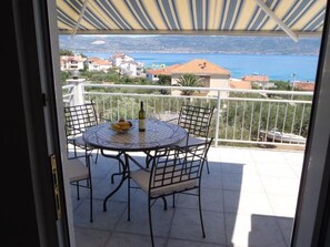 Enjoy a seaside view from this balcony with a table and chairs.