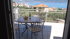 Ein Balkon mit Tisch und Stühlen, mit Blick auf die Küste.