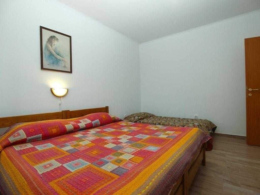 Une chambre à coucher avec un lit, une table de chevet, une lampe fixée au mur et une porte.