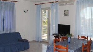 A living room with a sofa, a dining table with chairs, a TV, and a plant. - Apartment in Ražanj with Seaview, Terrace, Air condition, WIFI (5150-1) (Ražanj)