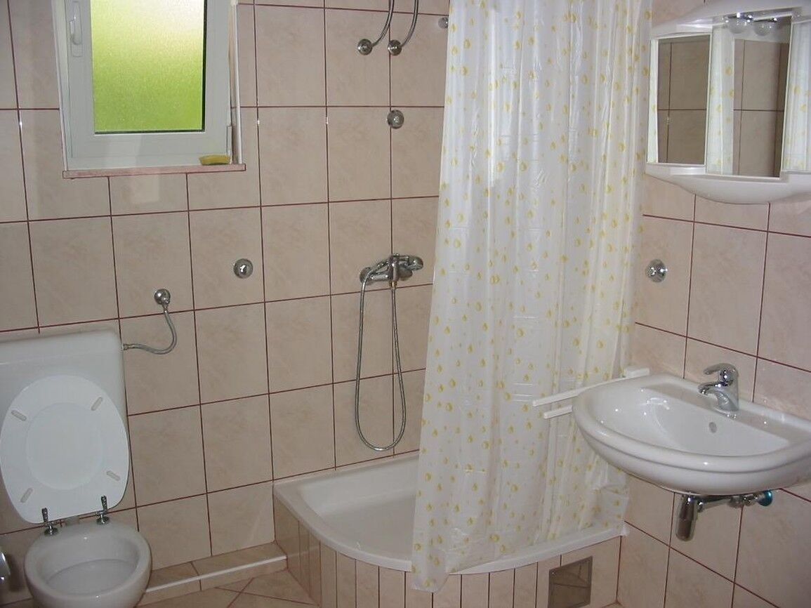 A bathroom with a toilet, bidet, bathtub, and sink.